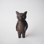 魚のけりぐるみを抱える黒猫を木彫りで作りました